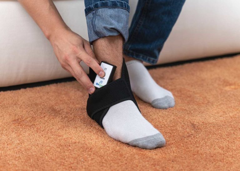 Person pressing button on controller for the OnLux Ankle Pad.