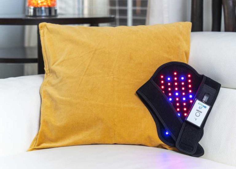 OnLux Knee Pad with lights on resting on yellow pillow.